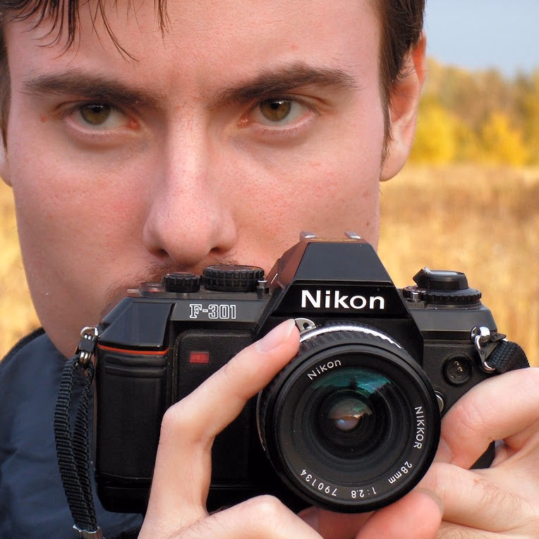 Sergey Pesterev with a Nikon F-301 film camera in an autumn field