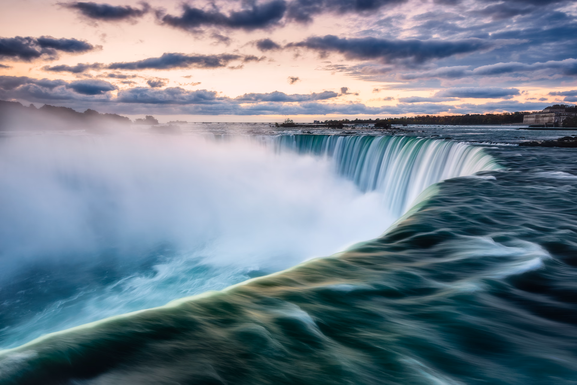 Niagara Falls at dawn: the curved brink of the falls and a cloud of spray, Canada